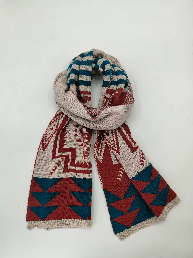 Gefalteter Strickschal mit geometrischem Südwest-Muster in Creme, Rostrot und Petrolblau auf weißem Hintergrund