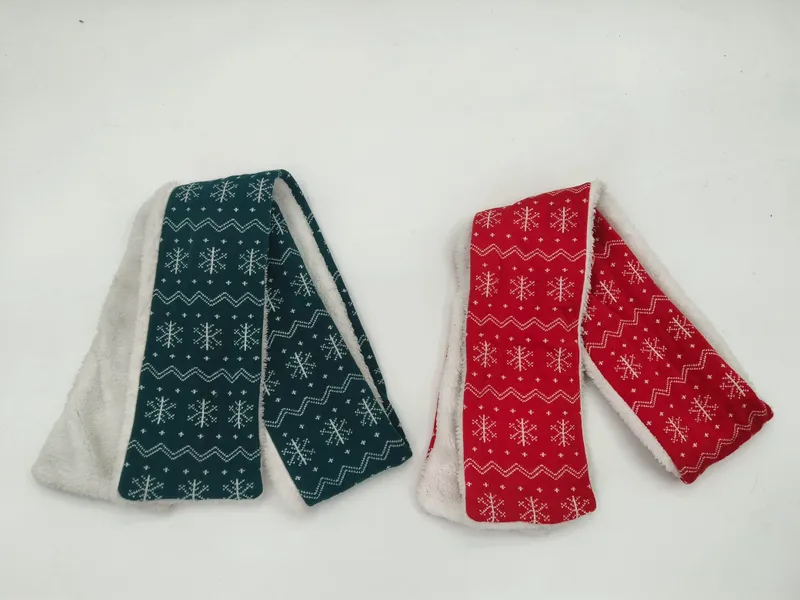 Zwei gefaltete Schals mit weißem Schneeflocken-Fair-Isle-Muster in Petrol und Rot mit sichtbarem Sherpa-Fleecefutter auf weißem Hintergrund