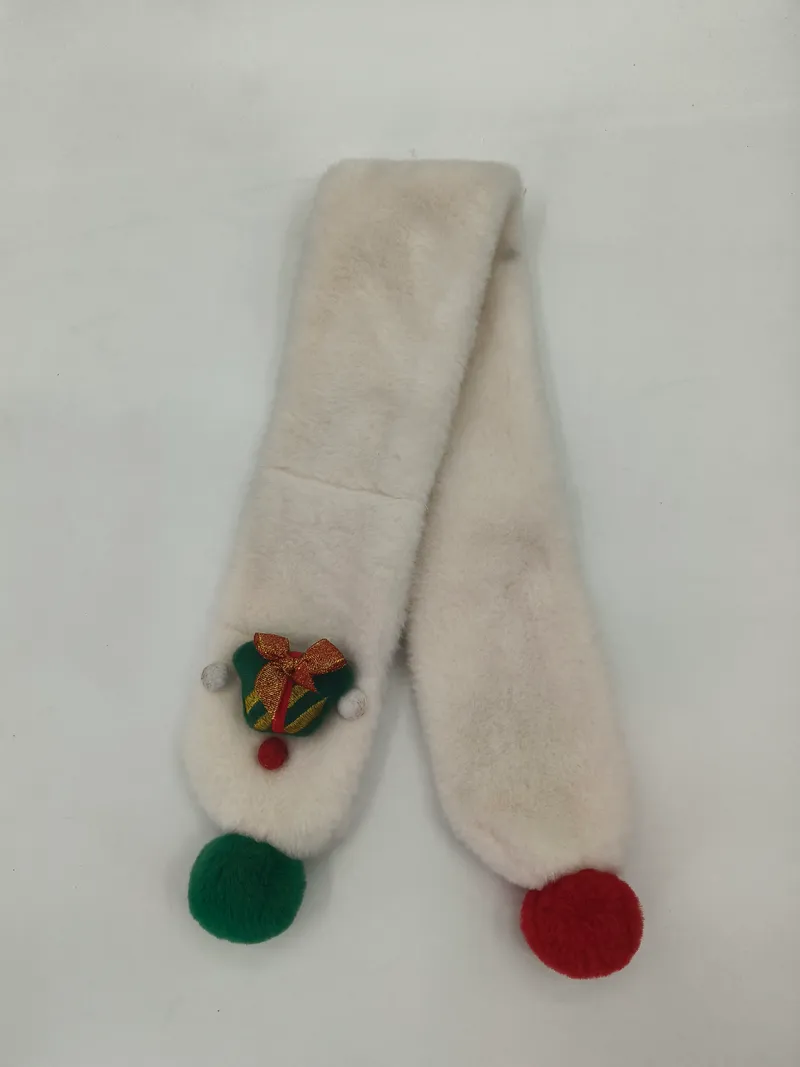 Cremefarbener Kunstfell-Schal mit grünen und roten Wollbommeln und bestickter Weihnachtsglocken-Brosche auf weißem Hintergrund