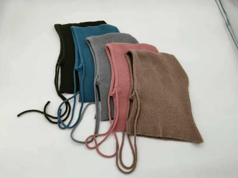 Fünf gerippte Babymützchen mit Kinnbändern in Oliv, Blau, Grau, Rosa und Taupe flach ausgelegt auf weißem Untergrund