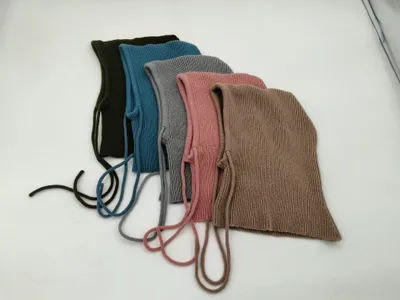 Fünf gerippte Babymützchen mit Kinnbändern in Oliv, Blau, Grau, Rosa und Taupe flach ausgelegt auf weißem Untergrund