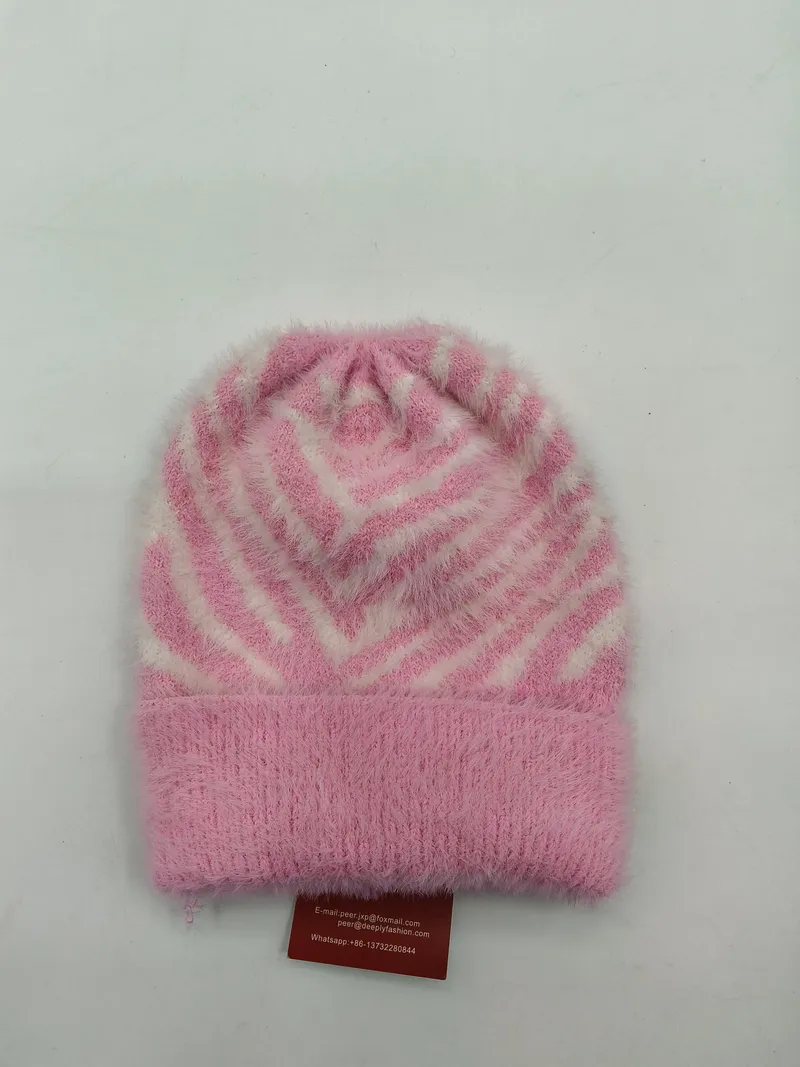 Rosa-weiße Flausch-Strickmütze mit geometrischem Chevron-Streifenmuster und umgeschlagenem Rand in Draufsicht auf weißem Hintergrund