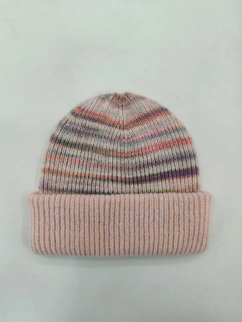 Flauschige Wintermütze mit bunten Streifen in Rosa, Lila und Grau sowie breitem gestricktem Umschlagrand auf weißem Untergrund