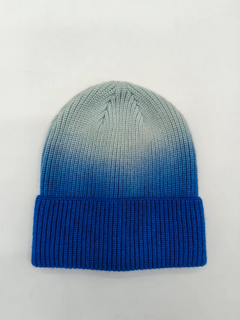 Strukturierte Wintermütze mit markanter Farbverlauf-Optik von Taubenblau zu Grau, flach aufgenommen auf hellem Hintergrund