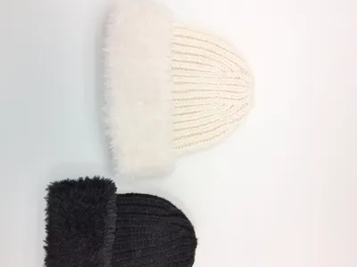 Zwei voluminöse Rippstrickmützen mit weichem Kunstfell-Umschlagrand in Cremeweiß und dunklem Anthrazit, flach fotografiert