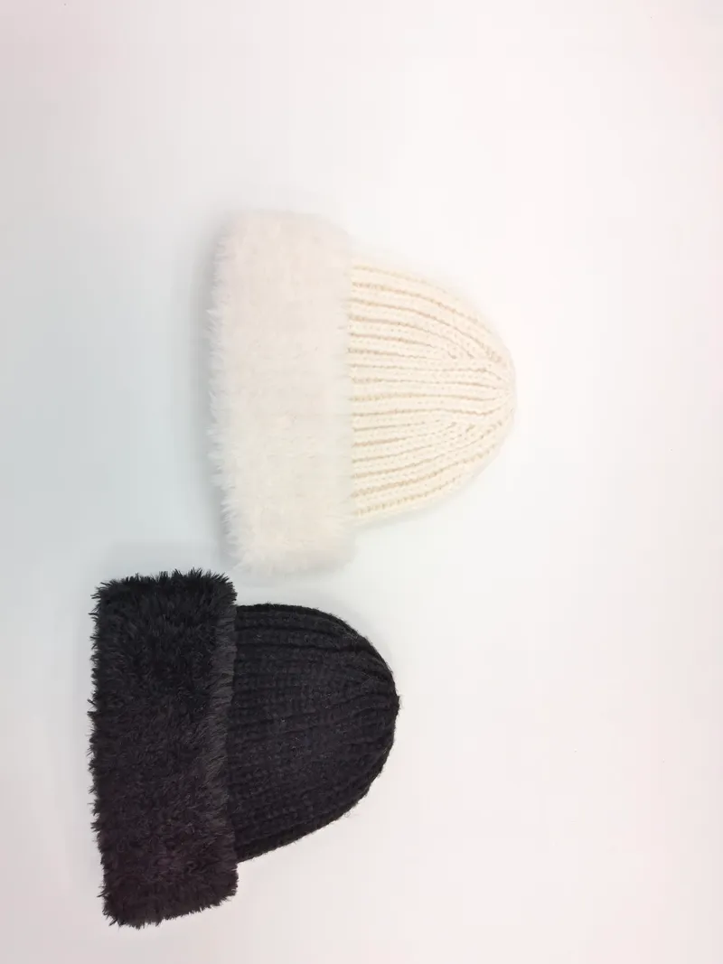 Zwei voluminöse Rippstrickmützen mit weichem Kunstfell-Umschlagrand in Cremeweiß und dunklem Anthrazit, flach fotografiert