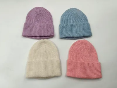 Vier zarte Rippstrickmützen in Pastell-Lavendel, Himmelblau, Vanille und Blassrosa nebeneinander auf weißer Fläche