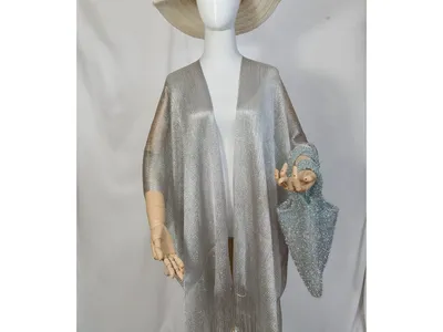 Schaufensterpuppe in silbernem Metallic-Kimono mit Fransen am Saum, kombiniert mit breitem Strohhut und blauer Glitzertasche