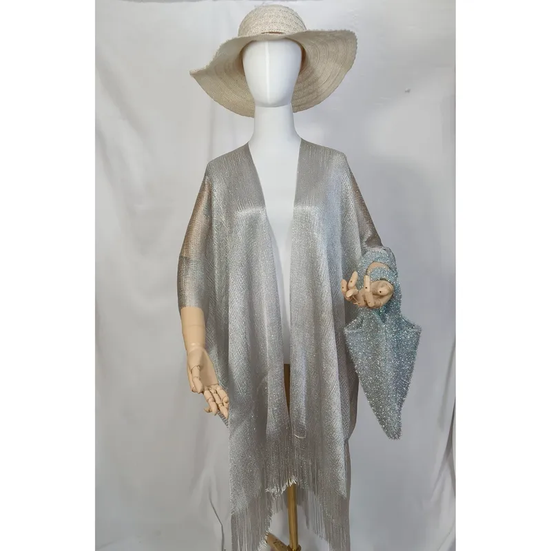 Schaufensterpuppe in silbernem Metallic-Kimono mit Fransen am Saum, kombiniert mit breitem Strohhut und blauer Glitzertasche