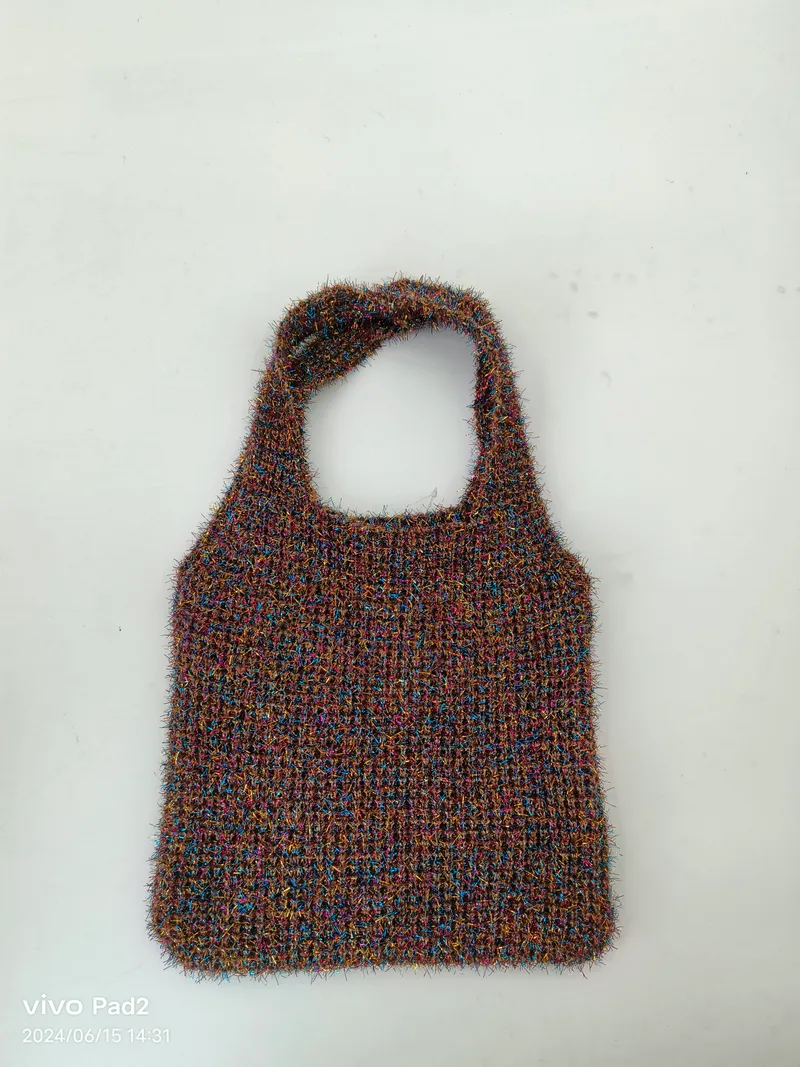 Handgestrickte flauschige Tragetasche aus buntem Garn in Braun, Blau und Rosa mit einfachem Schlaufengriff auf weißem Hintergrund