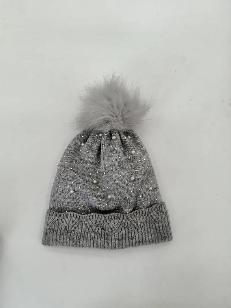 Graue Wintermütze aus Strick mit Zopfmuster-Bündchen, aufgestreuten Perlen und funkelnden Kristallsteinen sowie flauschigem Bommel