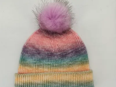 Bunt gestrickte Ombré-Mütze mit Farbverlauf in Rosa, Lila, Türkis und Gelb sowie lavendelfarbenem Kunstfell-Pompon