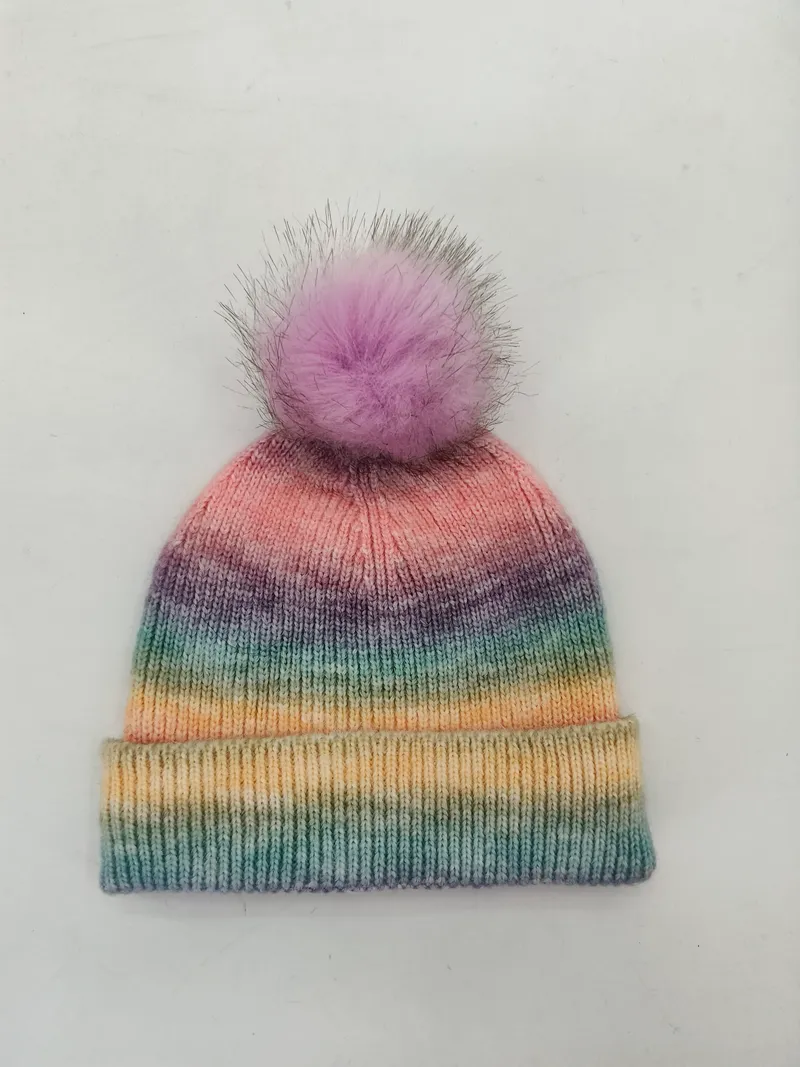 Bunt gestrickte Ombré-Mütze mit Farbverlauf in Rosa, Lila, Türkis und Gelb sowie lavendelfarbenem Kunstfell-Pompon