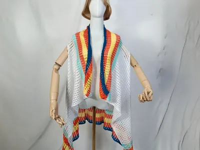 Weiße ärmellose Häkel-Cardigan mit bunten Streifen in Orange, Blau, Gelb, Türkis auf Schneiderpuppe mit Hut