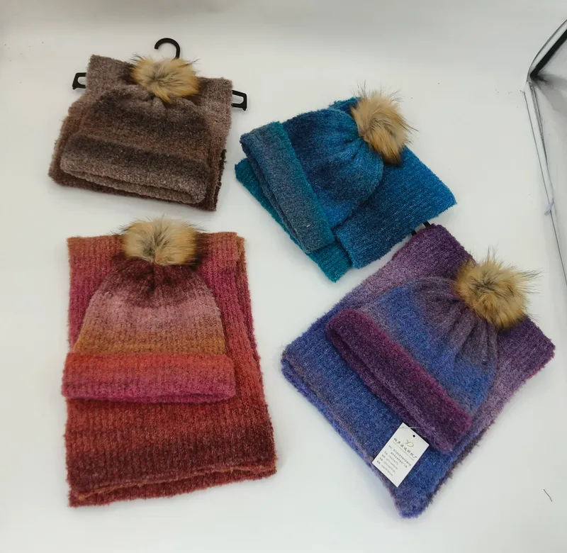 Vier verschiedene Stricksets mit Mütze und Schal in Braun, Blau, Rot-Orange und Lila-Farbverlauf, jeweils mit Kunstfell-Bommel