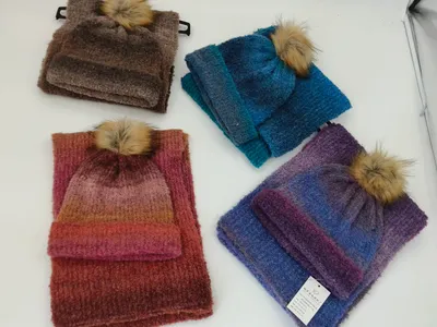 Vier verschiedene Stricksets mit Mütze und Schal in Braun, Blau, Rot-Orange und Lila-Farbverlauf, jeweils mit Kunstfell-Bommel