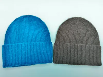 Zwei Rippenstrick-Beanies mit Umschlagbündchen nebeneinander – eine in kräftigem Blau, eine in warmem Sandbraun, auf weißem Hintergrund