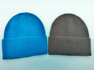 Zwei Umschlagbeanies aus Rippenstrick in leuchtendem Blau und warmem Hellbraun auf weißem Hintergrund nebeneinander