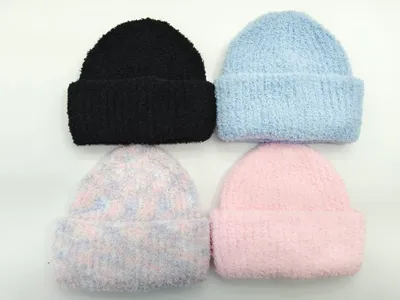 Vier weiche Plüschbeanies in Schwarz, Hellblau, Pastellrosa und mehrfarbigem Karomuster, flach auf weißem Untergrund angeordnet