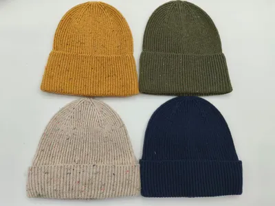 Vier Rippenstrick-Beanies in Senfgelb, Olivgrün, Haferflocken-Melange und Marineblau, flach auf weißem Untergrund