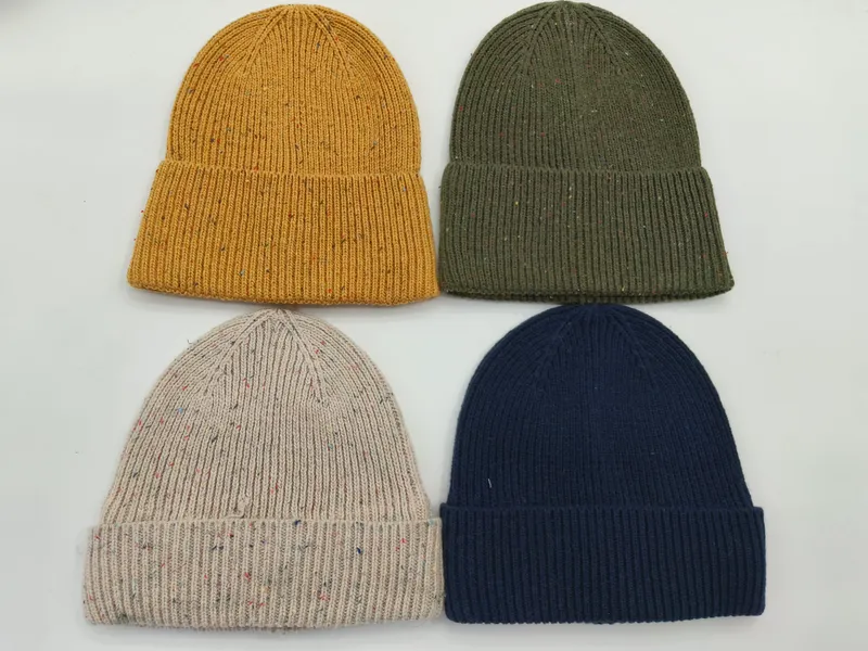 Vier Rippenstrick-Beanies in Senfgelb, Olivgrün, Haferflocken-Melange und Marineblau, flach auf weißem Untergrund