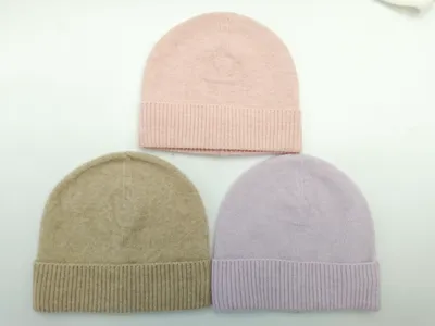 Drei gefaltete Rippenbündchen-Beanies in Altrosa, Taupe und Lavendel flach auf weißer Fläche liegend