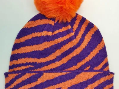 Strickmütze mit lila-orangenem Zebrastreifenmuster und großem orangefarbenem Kunstfellbommel auf der Spitze
