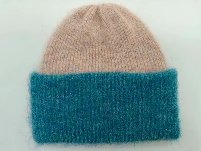 Flauschige Strickmütze mit weichem Oberteil in Altrosa und breitem geribbtem Umschlag in Petrolblau, Flachaufnahme auf hellem Hintergrund