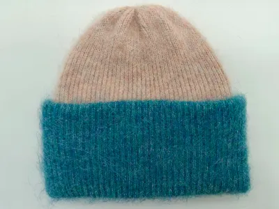 Flauschige Strickmütze mit weichem Oberteil in Altrosa und breitem geribbtem Umschlag in Petrolblau, Flachaufnahme auf hellem Hintergrund