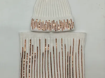 Weiße Rippenstrickmütze mit flauschigem Kunstfell-Bommel und Rosegold-Paillettenstreifen, kombiniert mit passendem Schlauchschal