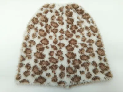 Nahaufnahme eines weichen Kunstfell-Stoffmusters mit braunem Leopardenfleckenmuster auf cremefarbenem Grund