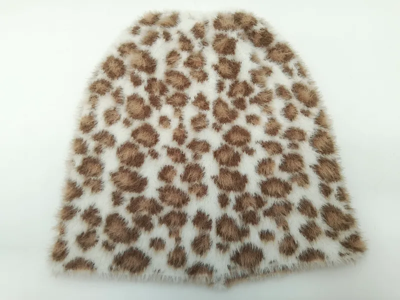 Nahaufnahme eines weichen Kunstfell-Stoffmusters mit braunem Leopardenfleckenmuster auf cremefarbenem Grund