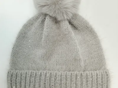 Hellgraue flauschige Winterstrickmütze mit großem Kunstfell-Bommel und silbernen Paillettenakzenten