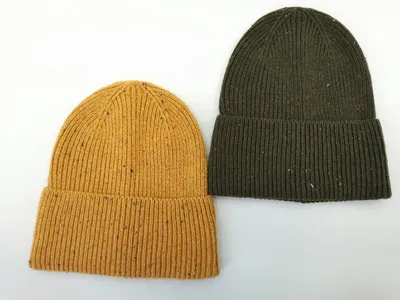 Zwei Rippenstrick-Beanies mit Umschlagbündchen und bunten Fleckdetails in Senfgelb und Olivgrün, Draufsicht auf weißem Hintergrund