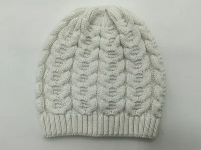 Weiße Zopfmuster-Wintermütze mit Blasenstich-Textur und gerippt abgesetztem Bündchen, auf hellem Hintergrund