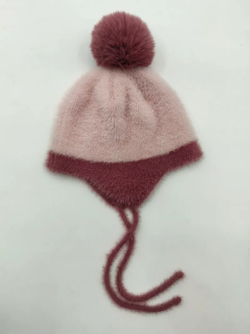 Altrosa flauschige Strickmütze mit Ohrklappen, dunkelmauvefarbenem Pompon und Bindebändern, Flachaufnahme
