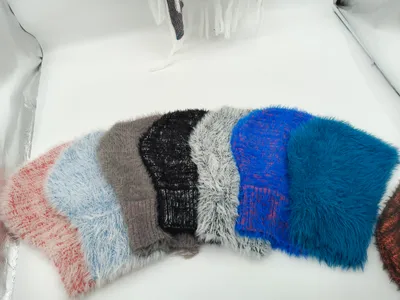 Sechs weiche Flausch-Strickmützen in Pink, Blau, Grau, Schwarz, Weiß und Royalblau, fächerförmig angeordnet auf weißem Hintergrund