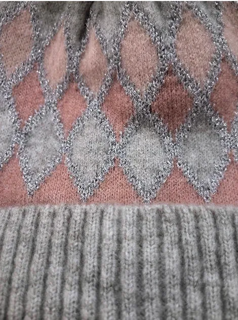Detailaufnahme einer Strickmütze mit rosa-grauem Rautenmuster, silbernen Metallic-Fäden und geripptem grauem Bund