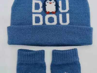 Blaues gestricktes Baby-Set aus Mütze und Handschuhen mit Pinguin-Grafik und Schneeflockendesign auf hellem Untergrund