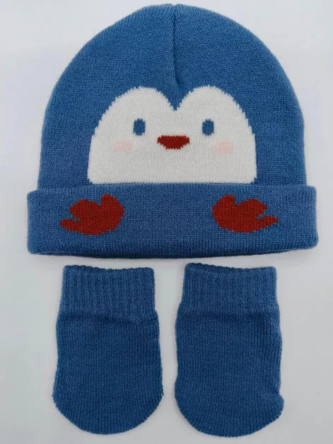 Blaue gestrickte Babymütze mit Intarsia-Pinguin-Gesicht und dazu passenden Babyhandschuhen auf weißem Hintergrund