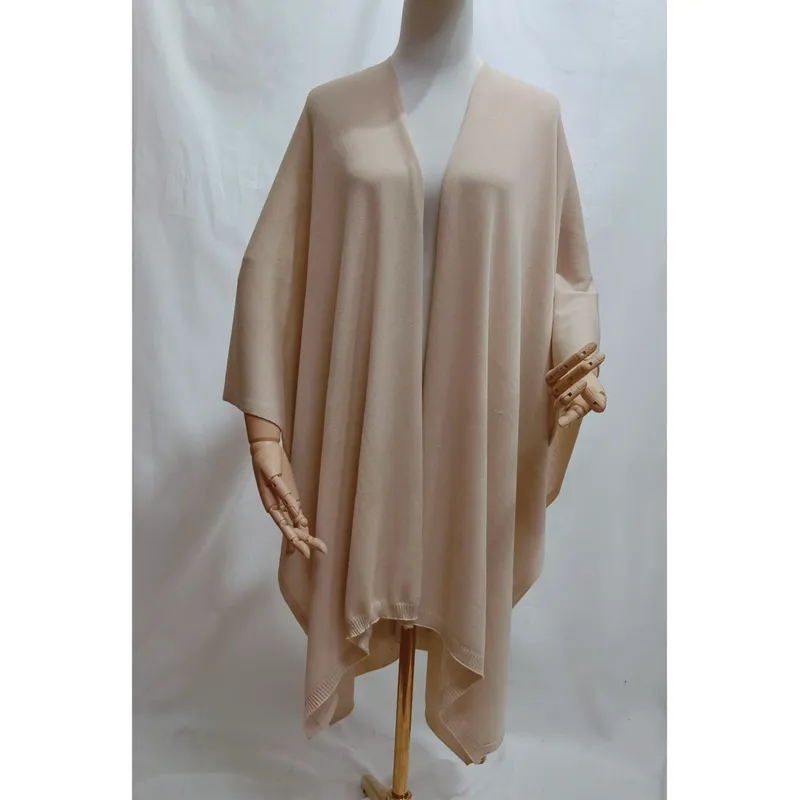 Creme-beigefarbener, großzügig geschnittener Strickponcho mit offenem Vorderteil und geripptem Saum auf einer Schneiderpuppe