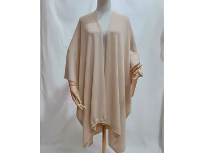 Beigefarbener, oversized Strickponcho mit offenem Vorderteil und geripptem Abschluss, drapiert auf einer Schneiderpuppe in neutralem Ton