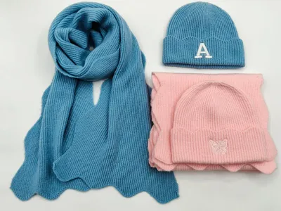 Blaues Rippstrick-Set mit gestickter Buchstabe-A-Mütze und pinkfarbener Beanie mit Schmetterlingsstickerei auf weißem Hintergrund