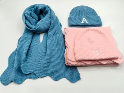 Blauer Rippstrickschal mit bestickter Buchstaben-Beanie und rosafarbene Schmetterlingsbeanie mit dazu passendem pinkfarbenem Schal im Set