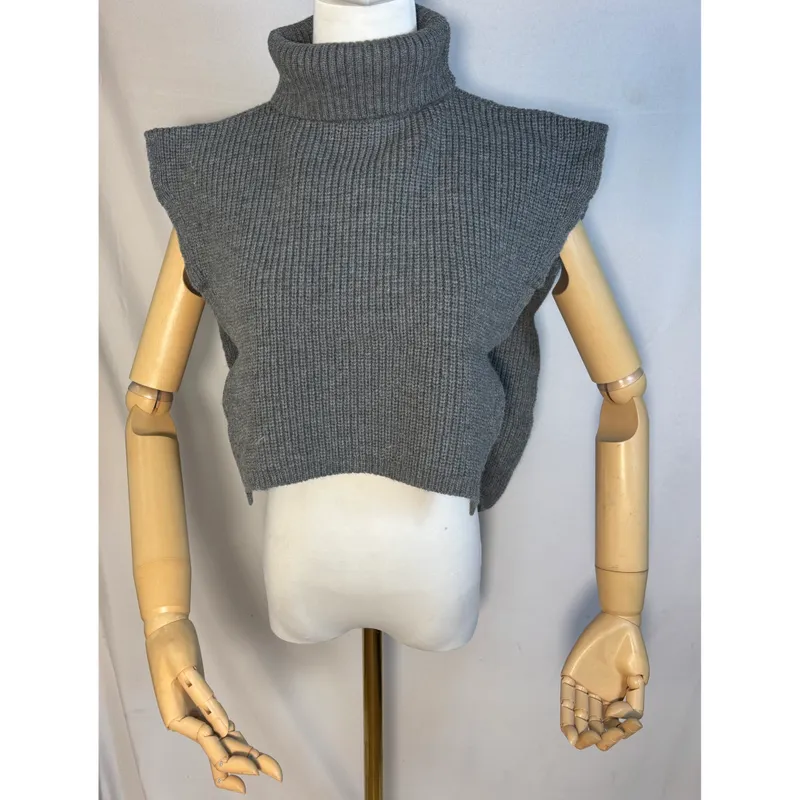 Ärmellose Strickweste in Grau mit Rollkragen und Rippenstruktur auf einer Schaufensterpuppe mit Holzarmen