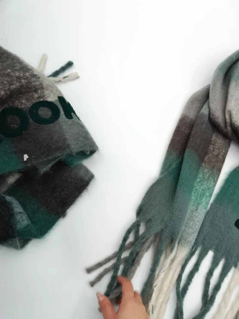 Zwei Karostoffe aus Wollmischung in Grün-Grau-Braun-Ombré mit Fransenenden, einer gefaltet und einer ausgebreitet auf weißem Untergrund