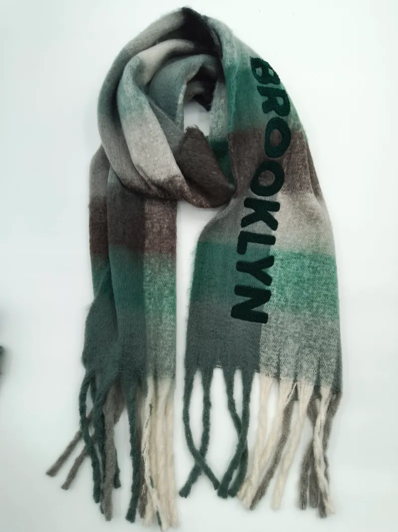 Gefalteter Karo-Schal mit Brooklyn-Schriftzug in Grün-Grau-Braun-Ombré und gedrehten Fransenenden auf weißem Hintergrund