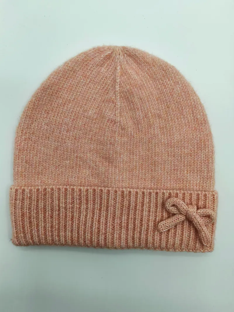 Zarte Strickmütze in Rosa-Melange mit dekorativer Schleife am gefalteten Bündchen, auf hellem Hintergrund