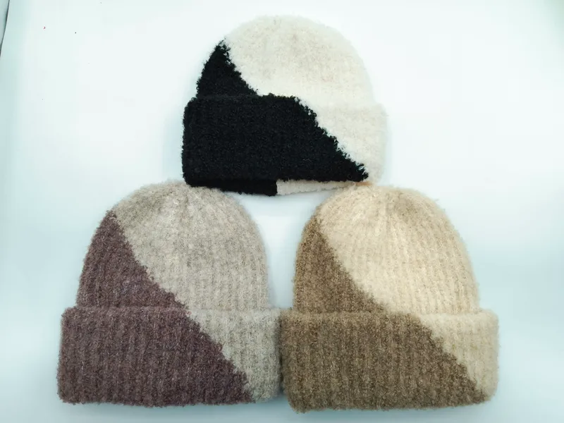 Drei flauschige Zweifarbmützen in Bouclé-Optik in den Farbkombis Schwarz-Creme, Mauve-Beige und Sand-Creme auf hellem Hintergrund