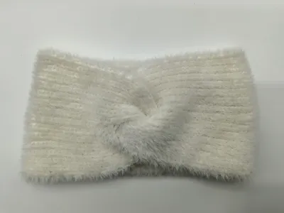 Weiches cremefarbenes Haarband aus flauschigem Rippstrick mit dekorativem Twist-Knoten in der Mitte, auf hellem Untergrund